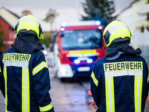 Feuerwehrleute vor Einsatzfahrzeug mit Blaulicht