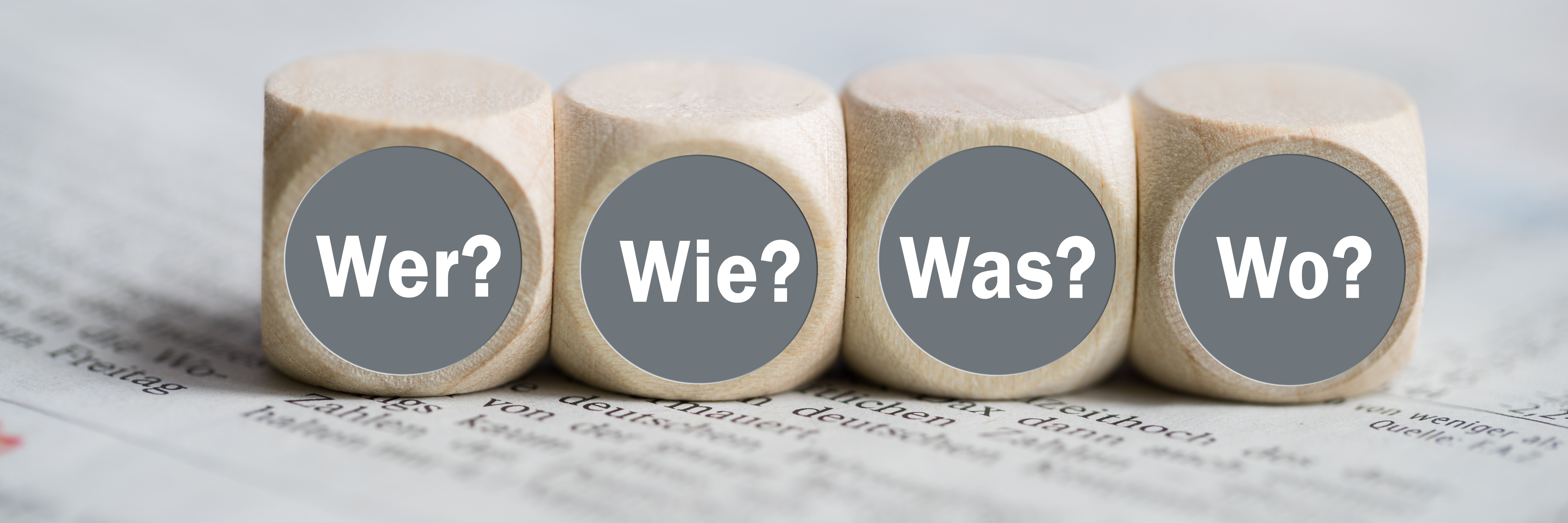 4 Würfel mit der Aufschrift Wer Wie Was Wo auf einer Zeitung