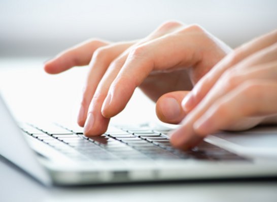 Zwei Hände machen Eingaben am Laptop