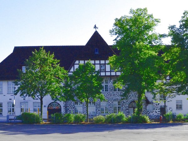 Panoramaufnahme im Frühling von der Grundschule Spormecke mit Schulhof, Bushaltestelle und daran angrenzendem Feuerwehrgebäude