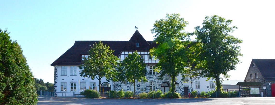 Grundschule Spormecke mit grün leuchtenden Bäumen davor