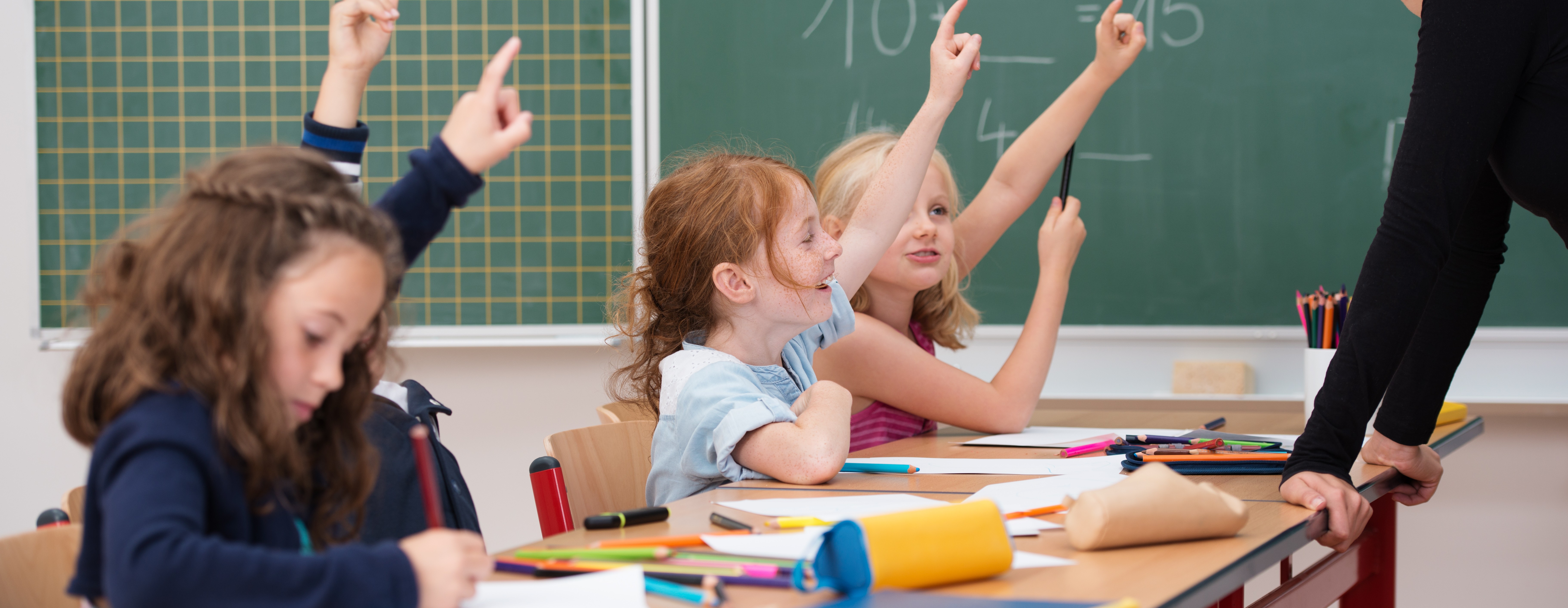 Kinder in der Schule melden sich um eine Aufgabe zu lösen