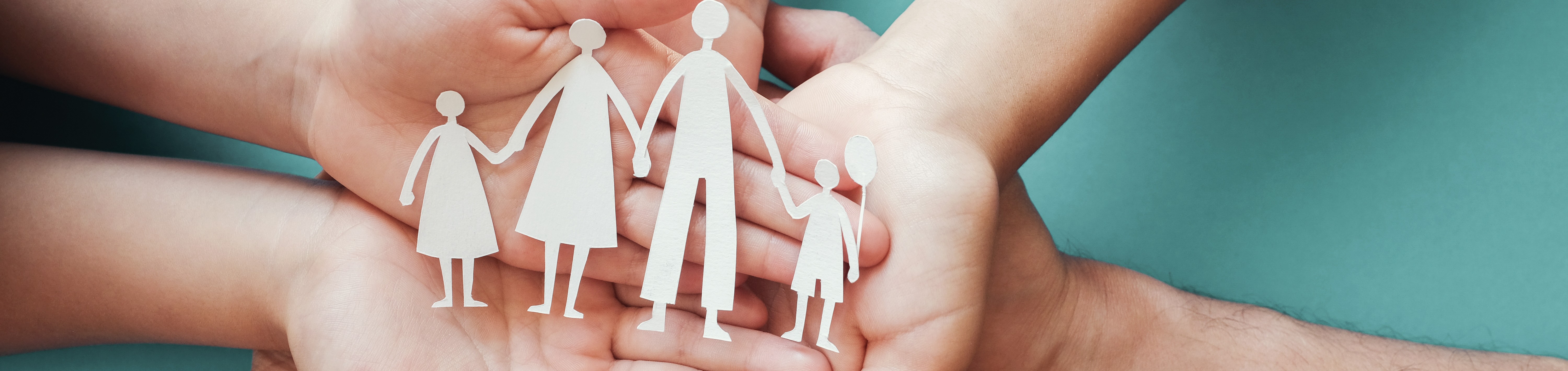 Hände halten eine Papierfamilie in der Hand
