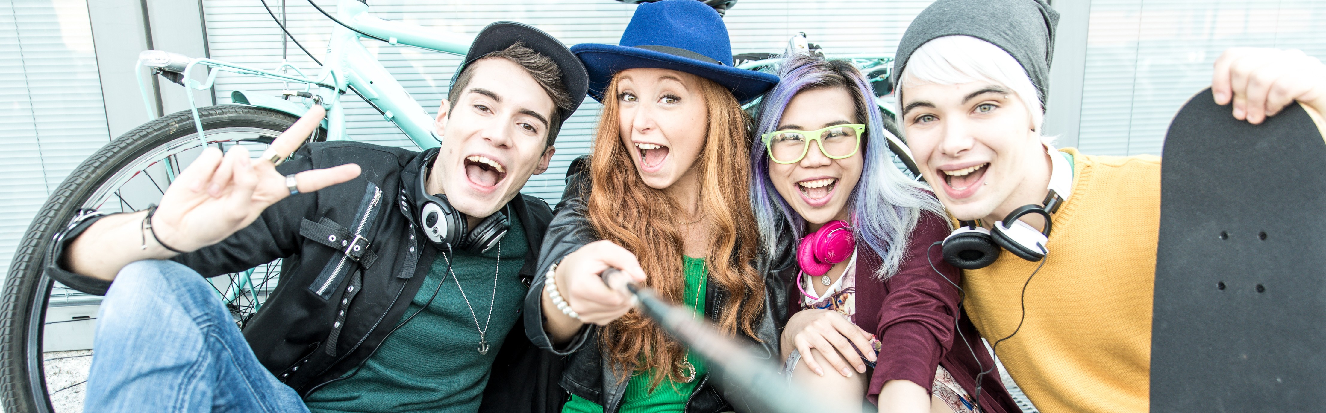 Gruppe von Teenangern sitzen im Freien und Fotografieren sich mit einem Selfiestab