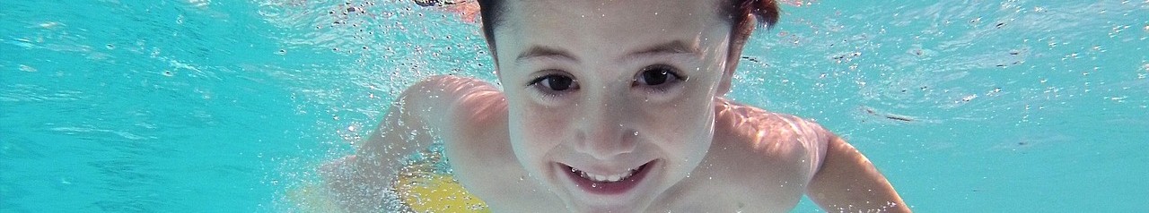 Kind taucht im Becken einer Schwimmhalle