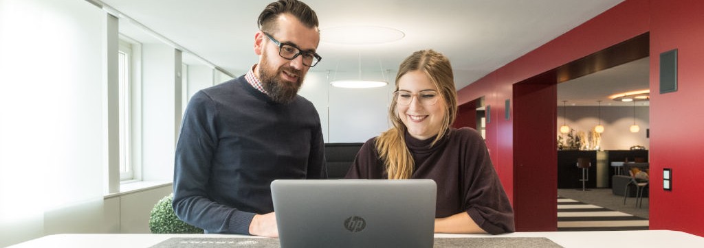 Eine Mitarbeiterin und ein Mitarbeiter besprechen sich gemeinsam an einem Laptop