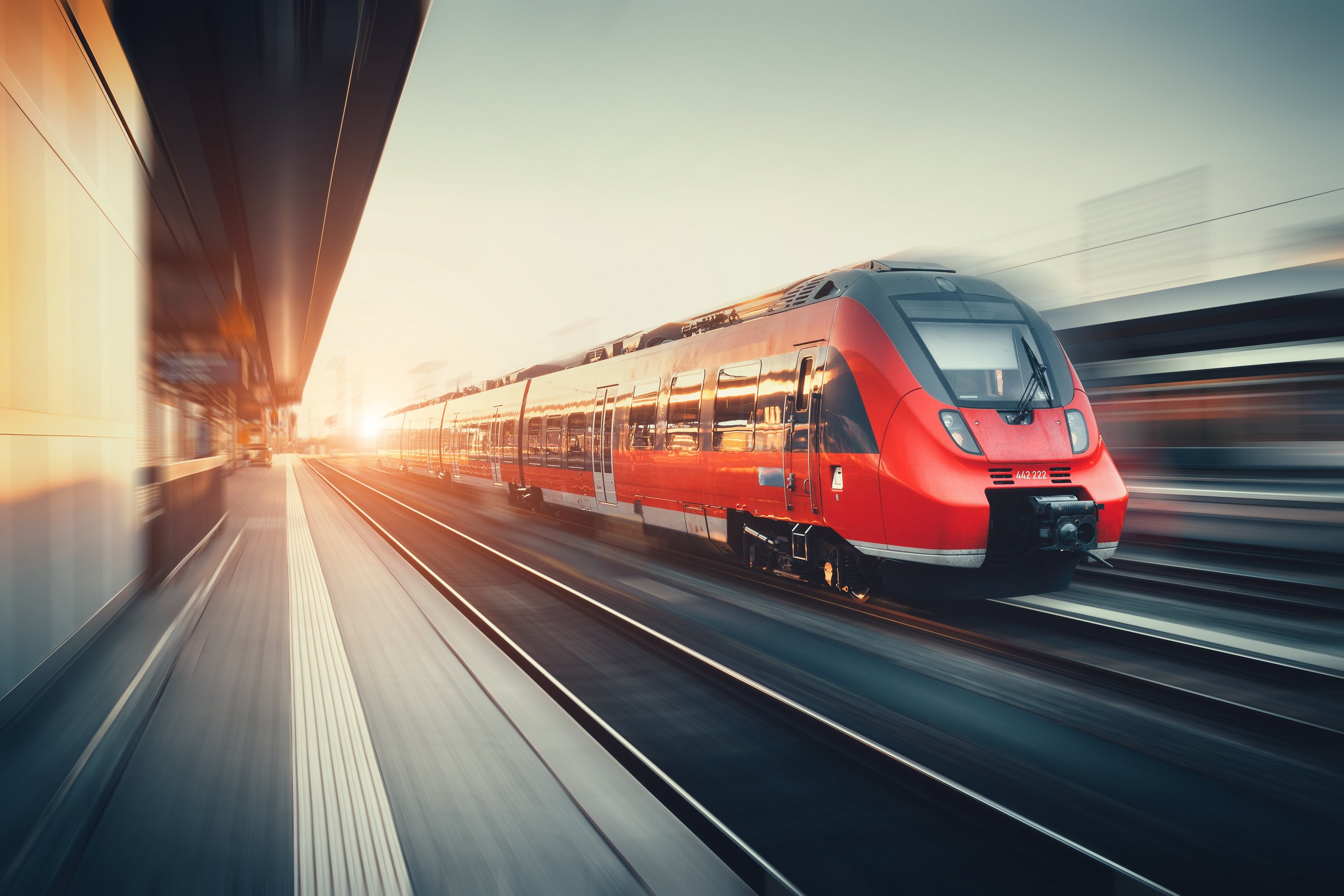 Bahnhof mit modernem roten Zug im Sonnenuntergang