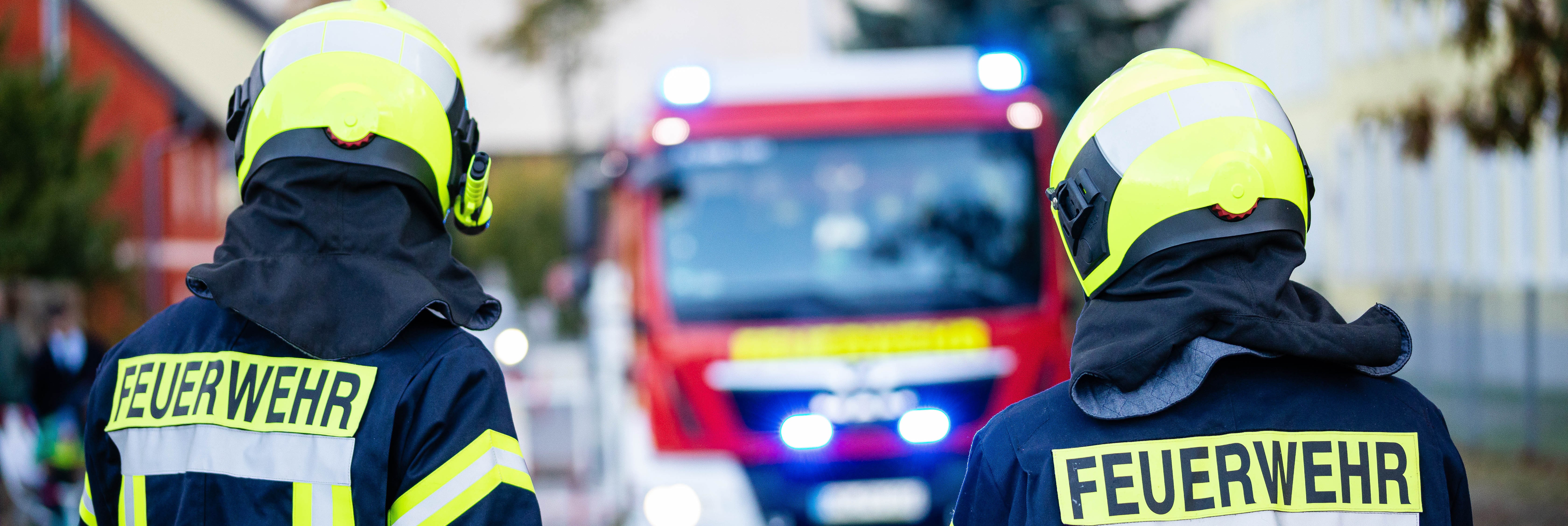 Feuerwehrleute vor Einsatzfahrzeug mit Blaulicht